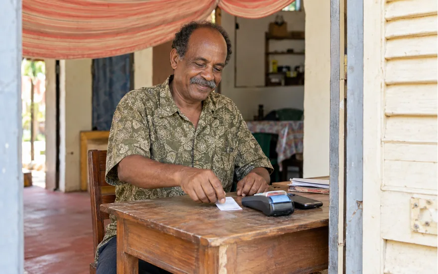 Tanzania mobile-money record scene with an adult, payment terminal, phone and printed receipt