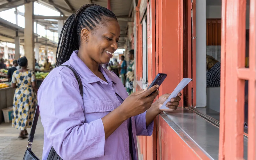 Wasafi Bet deposit checks illustrated by an adult comparing a mobile-money receipt with a phone in a covered arcade